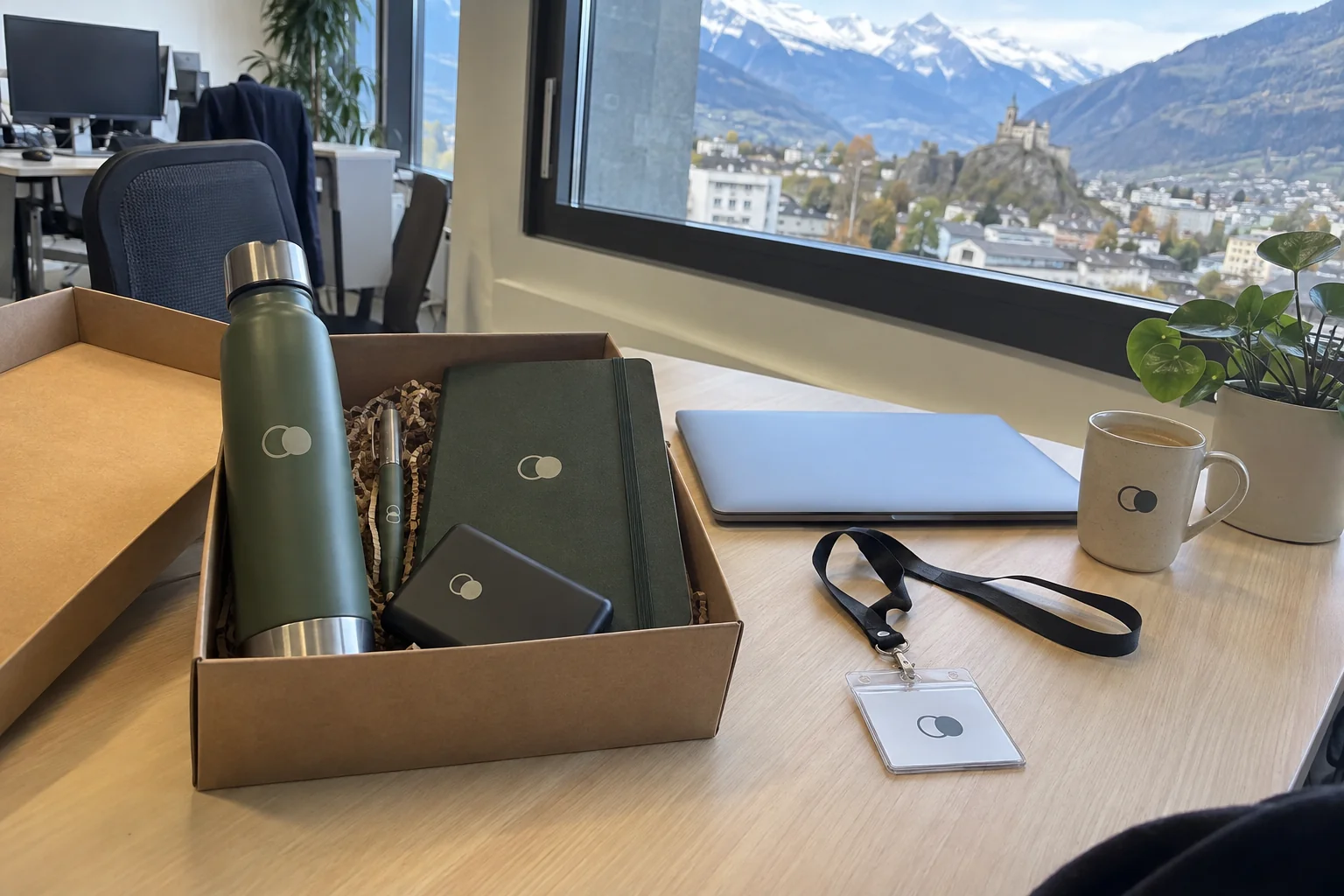 Personalised welcome pack with water bottle, notebook, pen and power bank on a desk overlooking Sion