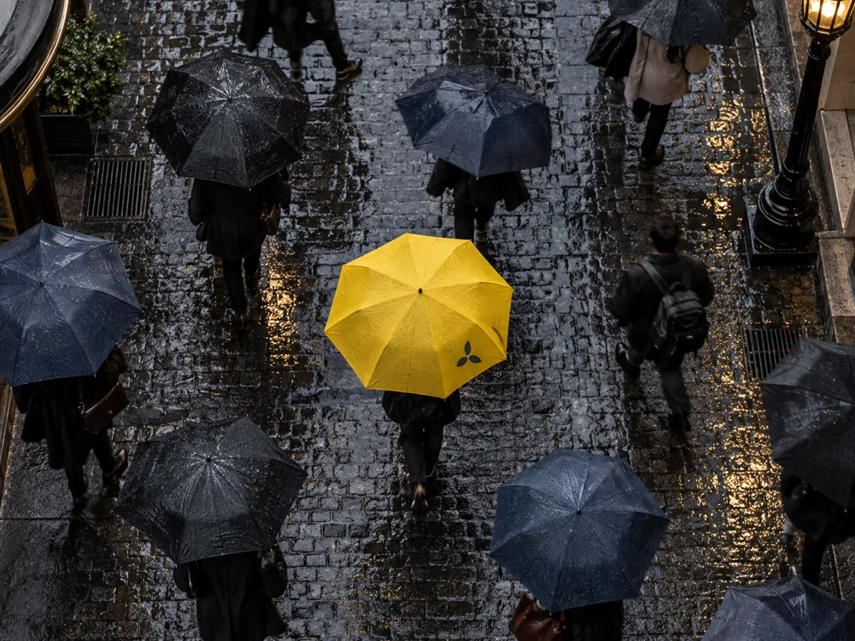 Personalisierter gelber Regenschirm mit Logo zwischen Passanten im Regen